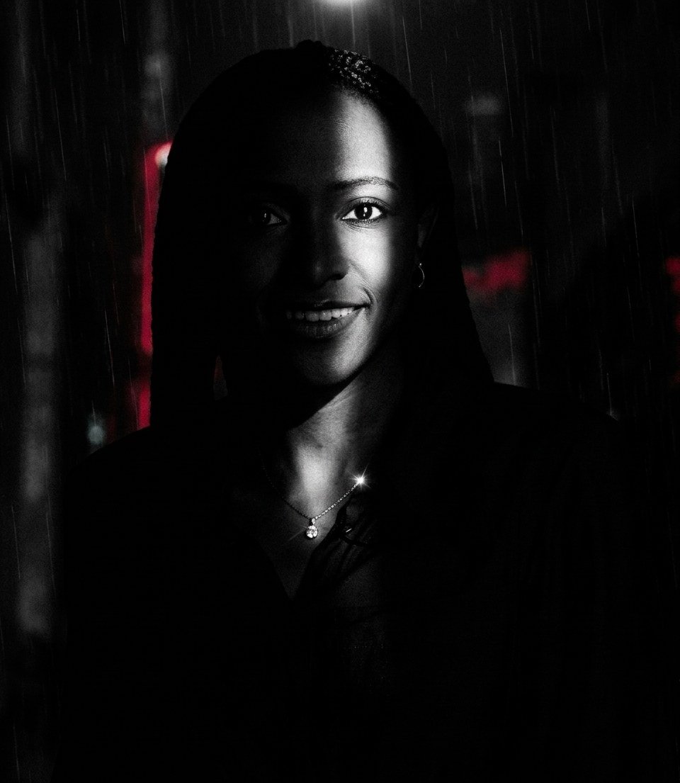 Smiling woman with long braids in dramatic low light