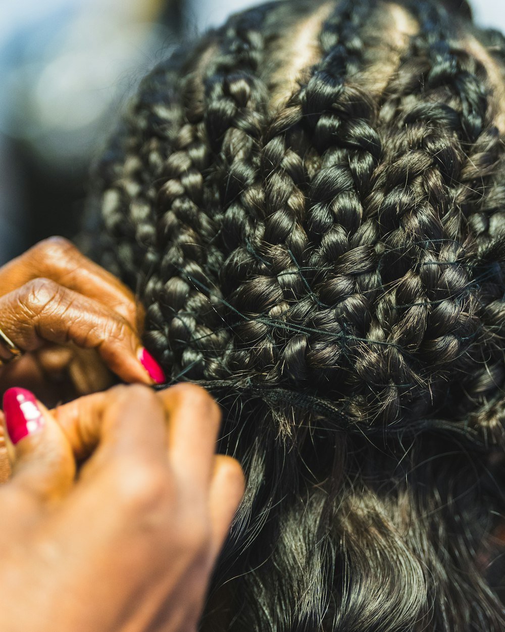 Hands braiding a client's hair with blue braiding hair