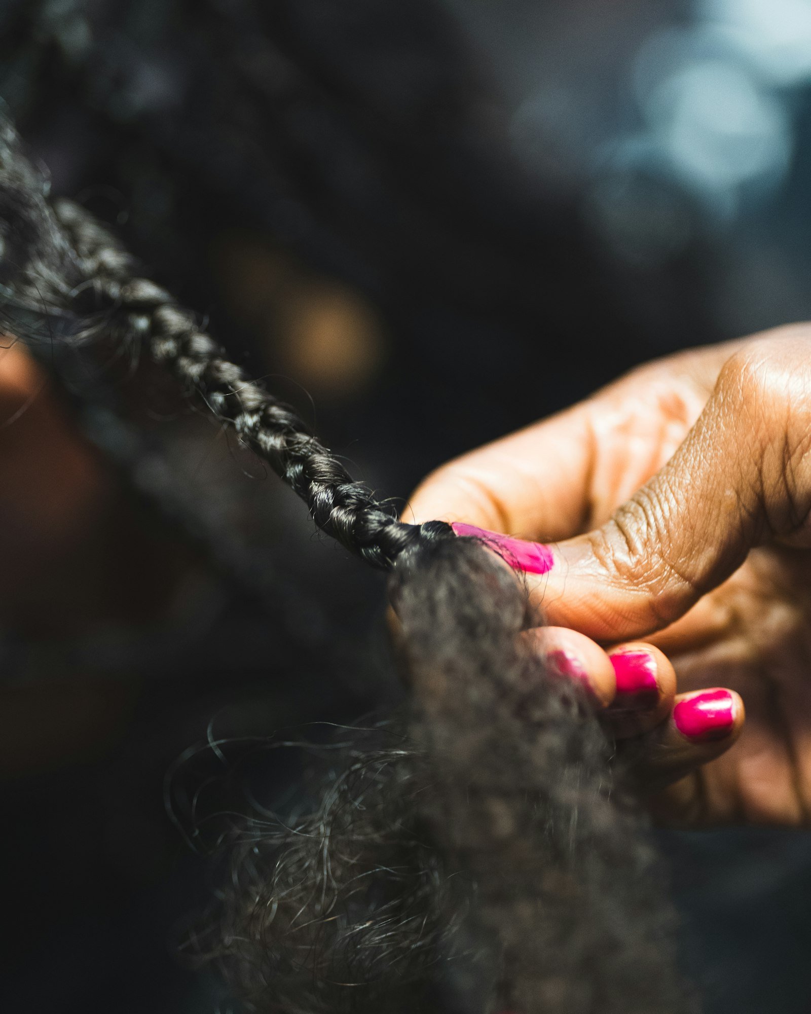 Braider's hands working on a section of natural hair